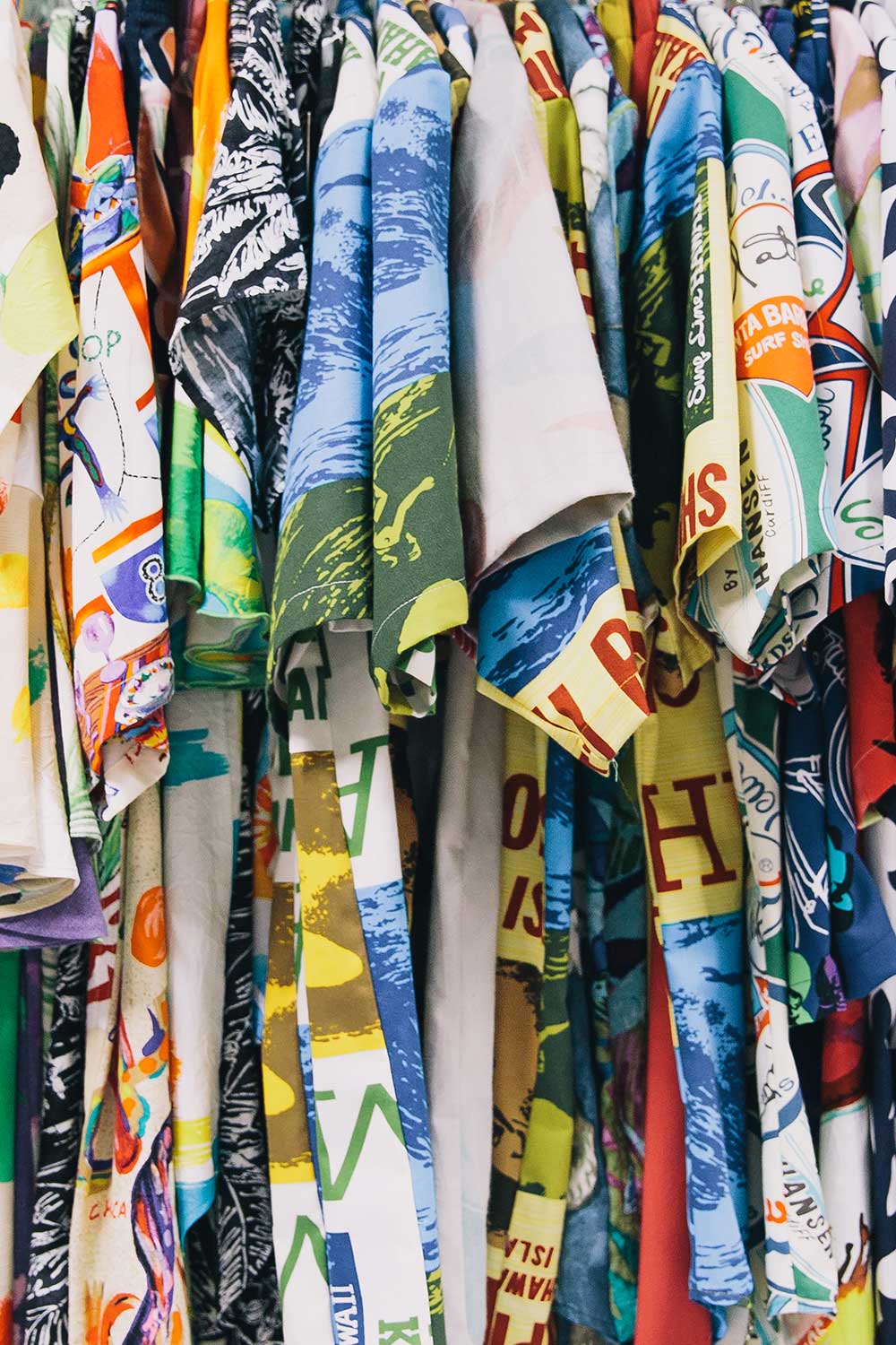 An assortment of aloha shirts hanging on a rack.
