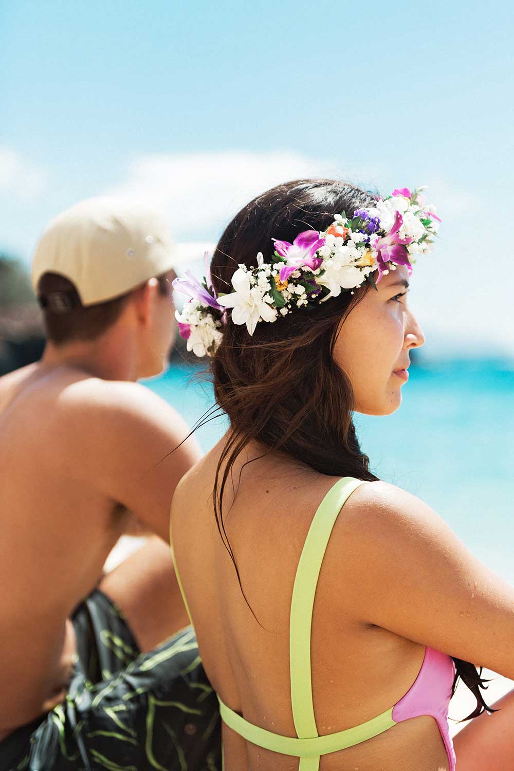 Roundup-North-Shore_2 Woman with lei in hair and man sitting near ocean